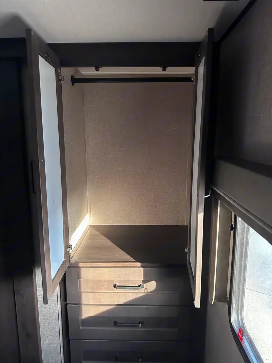 RV rental: Inside, an open wardrobe features a hanging rod, a shelf, and three drawers for storage.. Grand Design Reflection 2022