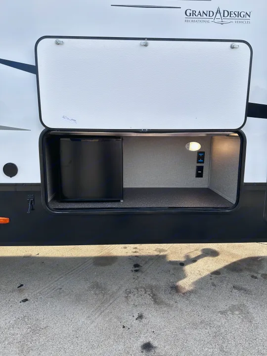 RV rental featuring an open exterior storage bay with a mini-fridge, interior light, and power outlets.. Grand Design Reflection 2022