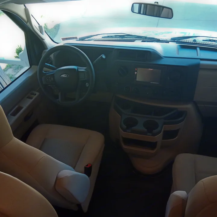 RV rental cockpit: Inside view of the driver's area, featuring a Ford steering wheel, dashboard, and front seats.. Thor Four Winds 2022