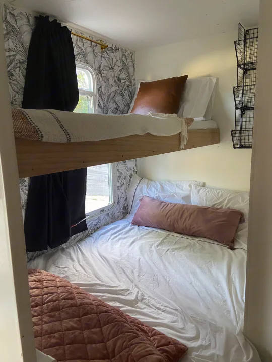 Experience cozy RV rental living: detailed bunk beds with tropical wallpaper, black curtains, and a smart wall storage unit.. Jayco Jay Flight 2007