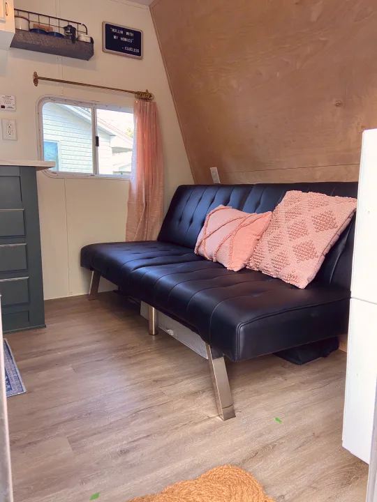 Inviting RV rental interior: black sofa bed, pink pillows, light wood walls & vinyl plank floors. Perfect for road trips!. Jayco Jay Flight 2007