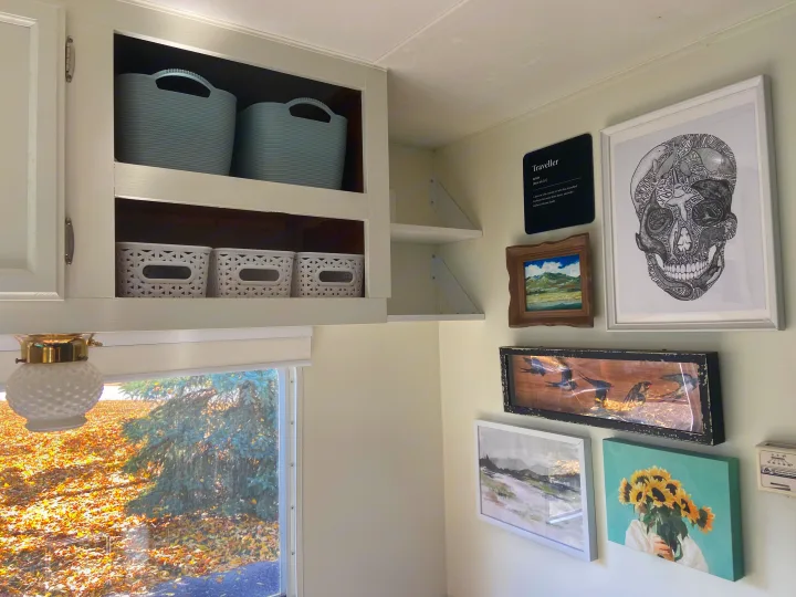 This RV rental features organized white cabinets, diverse wall art including a "Traveller" sign, and a vibrant autumn window view.. Jayco Jay Flight 2007