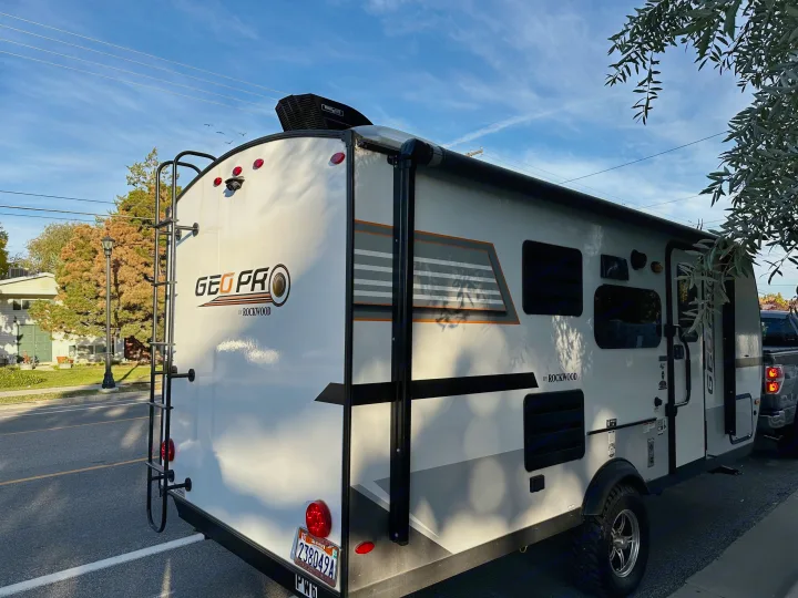 Rear view of a white Geo Pro by Rockwood travel trailer, ideal for an RV rental, parked on a street under a bright sky.. Forest River Rockwood GeoPro 2019