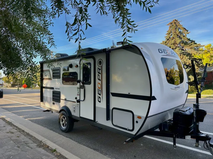 A sleek white and grey Rockwood Geo Pro travel trailer, perfect for an RV rental adventure, parked curbside on a sunny day.. Forest River Rockwood GeoPro 2019