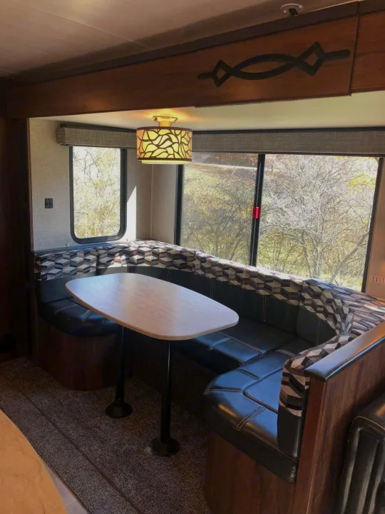 Spacious RV rental dinette featuring U-shaped seating, a modern table, and large windows with scenic views. Ideal for travel.. Heartland RVs Mallard 2019