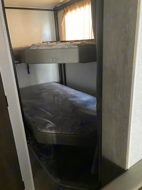 RV rental interior: A compact sleeping area featuring a folded bunk bed on the right and another bunk with a bright window.. Forest River Salem 2020