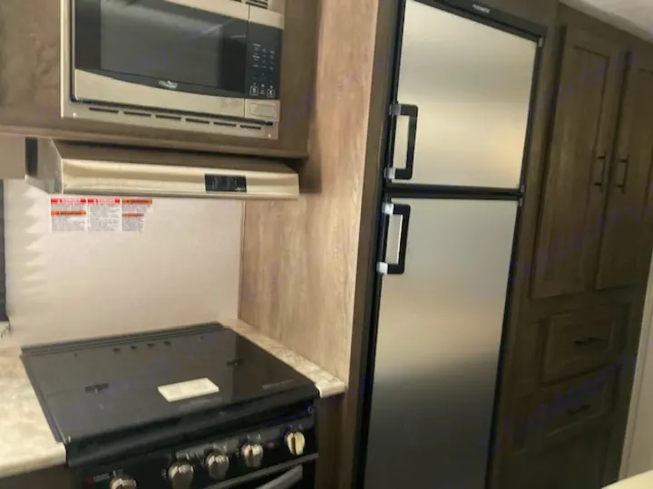 RV rental kitchen featuring microwave, range hood, stove with cover, and refrigerator. Ideal for mobile living.. Forest River Salem 2020