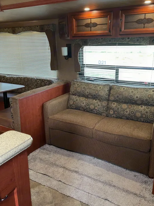 An inviting rv rental interior showcasing a dining area, patterned sofa, and stylish wood cabinets.. Palomino Puma 2015