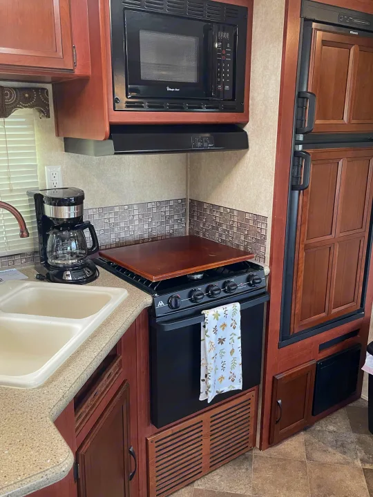 Inside an RV rental: a functional kitchen featuring a microwave, stove/oven, fridge, sink, and coffee maker.. Palomino Puma 2015