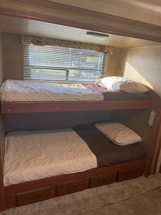 Inside a comfortable RV rental: bunk beds, natural light from blinds, and built-in storage drawers below.. Palomino Puma 2015