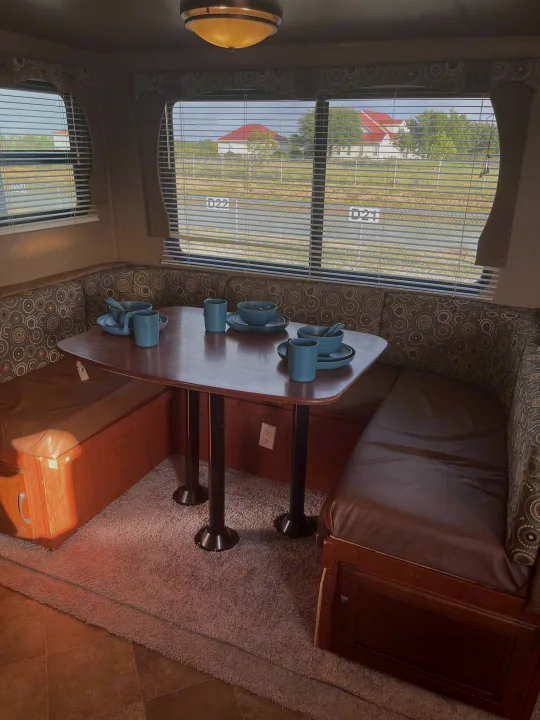 Cozy RV rental dinette with U-shaped booth, wooden table, and blue dishware, offering a view outside.. Palomino Puma 2015