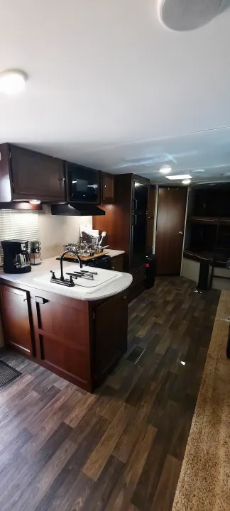 An inviting RV rental interior, showcasing a fully equipped kitchen, comfortable living space, and wood laminate floors.. Keystone RV Bullet Ultra Lite 2016