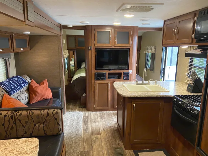 Comfortable RV rental interior showing a full kitchen, living area, and bedroom, perfect for travel.. Keystone Passport 2017