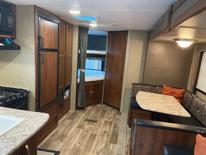 Spacious RV rental interior with a fully equipped kitchen, comfortable dinette, and a cozy bedroom area.. Keystone Passport 2017