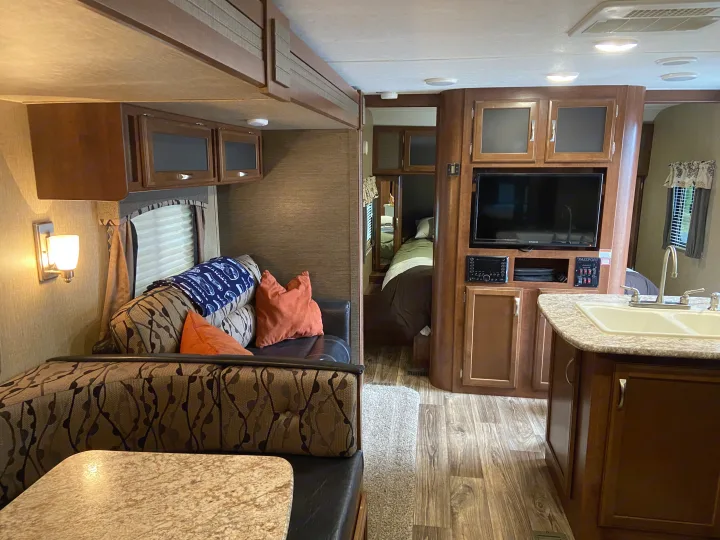 Cozy RV rental interior with comfy seating, a functional kitchen, and a private bedroom area.. Keystone Passport 2017