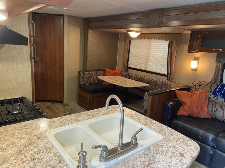 Explore the cozy interior of this RV rental, featuring a full kitchen, comfortable dinette, and inviting living area.. Keystone Passport 2017