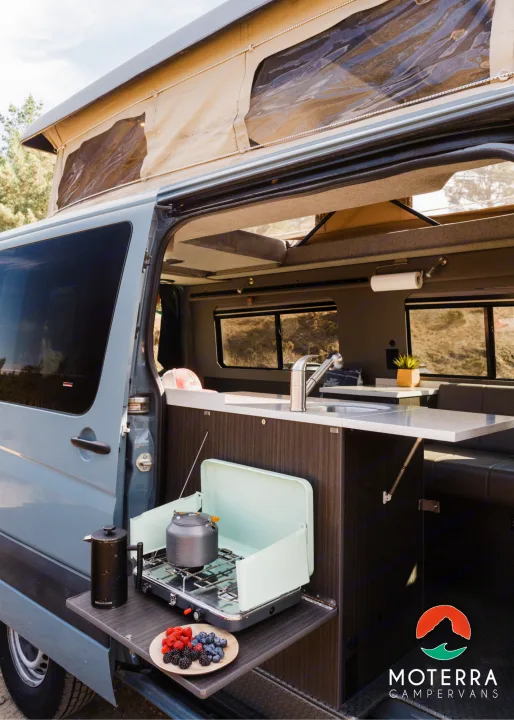 This RV rental showcases a grey pop-top campervan with an interior kitchen and an outdoor cooking station for easy camping.. Mercedes-Benz Sprinter 2021
