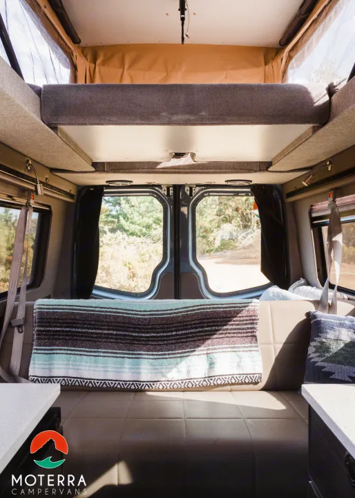 Cozy camper van interior ready for an RV rental adventure. Enjoy the pop-top bed & nature views from inside.. Mercedes-Benz Sprinter 2021