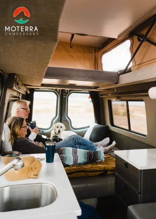 Enjoying an RV rental adventure: a couple and their dog relax inside a spacious Moterra camper van.. Mercedes-Benz Sprinter 2021