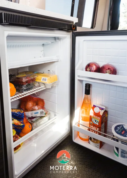 Stocked RV rental fridge with produce & drinks, showcasing convenient mobile kitchen amenities for your trip.. Mercedes-Benz Sprinter 2021