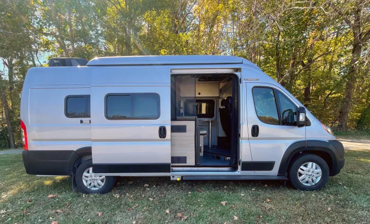Get ready for adventure! This silver RV rental camper van with open side door shows off its cozy interior.. Winnebago Solis PX 2023