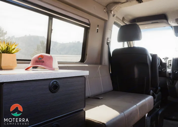 Bright RV rental camper van interior. Features a clean counter, comfortable seating, and scenic window views.. Mercedes-Benz Sprinter 2020