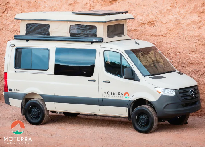 Beige Moterra pop-top RV rental campervan, parked on dirt against a red rock wall. Perfect for travel adventures.. Mercedes-Benz Sprinter 2020