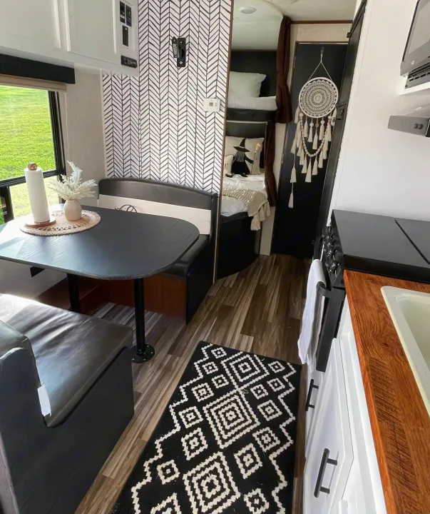 Modern RV rental interior featuring a black and white kitchen, dining area, and bunks, with stylish decor.. Jayco Jay Flight 2017