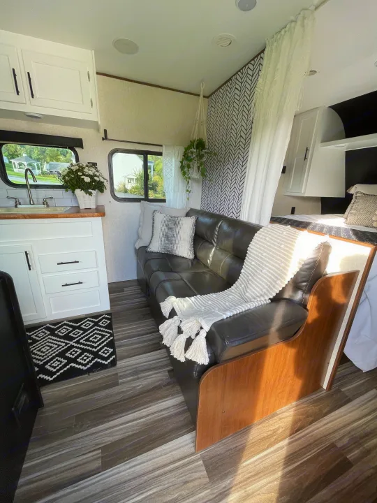 Cozy RV rental interior, featuring a black couch, white kitchen area, geometric wall, and inviting bedroom space.. Jayco Jay Flight 2017
