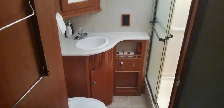 Step inside a tidy RV rental bathroom with a sink, cabinet, toilet, and shower cabin for your next adventure.. Winnebago Sightseer 2008