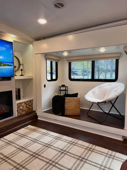 Cozy rv rental interior: Modern living space with TV, fireplace, soft chair, and large windows. Your comfortable getaway awaits.. Keystone RV Montana 2015