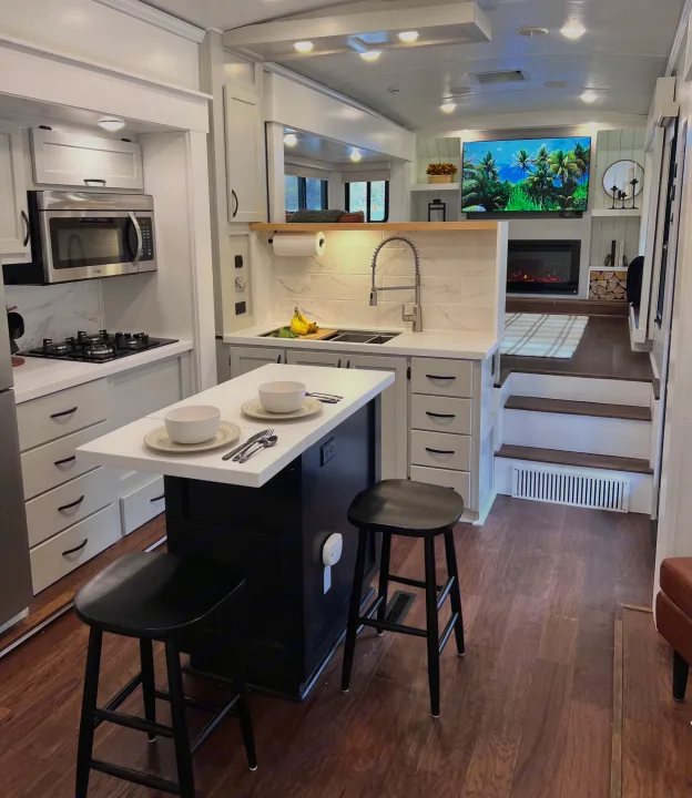 Luxury RV rental interior featuring a modern kitchen with island & stools, plus an inviting living area with TV & fireplace.. Keystone RV Montana 2015