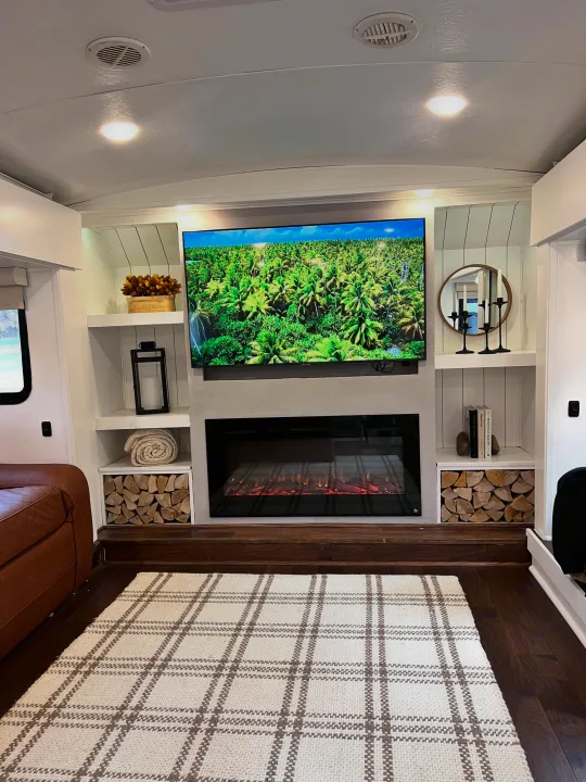 This inviting RV rental offers a well-appointed living room with a large TV, electric fireplace, and decorative shelving.. Keystone RV Montana 2015