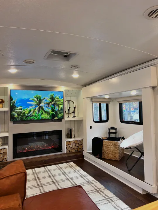 This bright, modern RV rental features a living area with TV, electric fireplace, storage, and a raised bedroom section.. Keystone RV Montana 2015