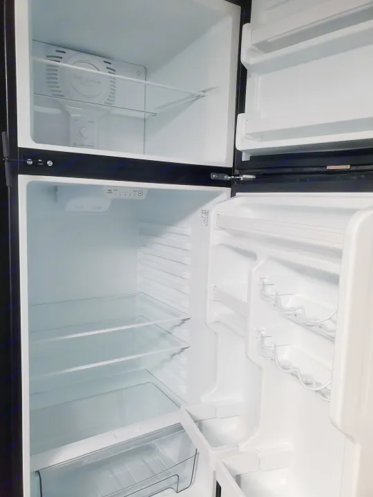 Inside an empty **rv rental** refrigerator with shelves, door compartments, and temperature controls, ready for use.. Forest River Sunseeker 2020