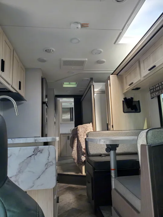Modern rv rental interior: bright kitchen, dining area, and hallway leading to rear. Ideal for road trips.. Forest River Sunseeker 2020