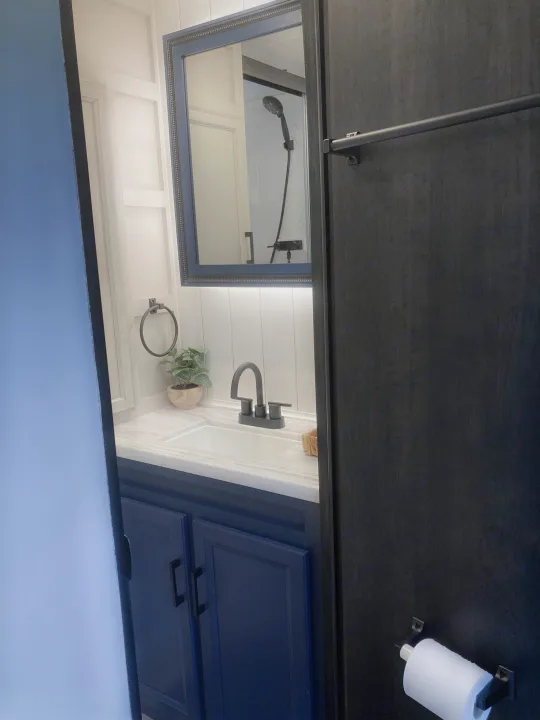 Well-appointed RV rental bathroom: blue vanity, sleek faucet, mirror, and toilet paper holder, reflecting the shower.. Jayco Eagle HT 2022
