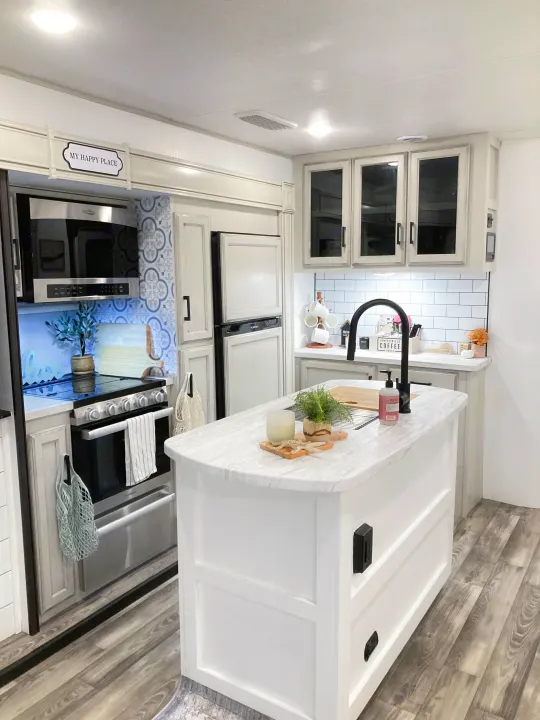 Modern and bright RV rental kitchen, featuring white cabinets, subway tile, stainless appliances, and a large island.. Jayco Eagle HT 2022