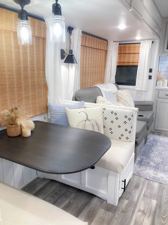 Modern RV rental interior with a cozy dining booth, gray recliners, wood-look flooring, and stylish, light-colored decor.. Jayco Eagle HT 2022