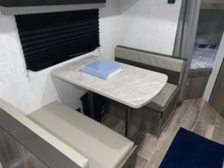 RV rental interior featuring a cozy dinette with light-colored benches & a table. Ideal for travel & camping.. Gulf Stream Enlighten 2022