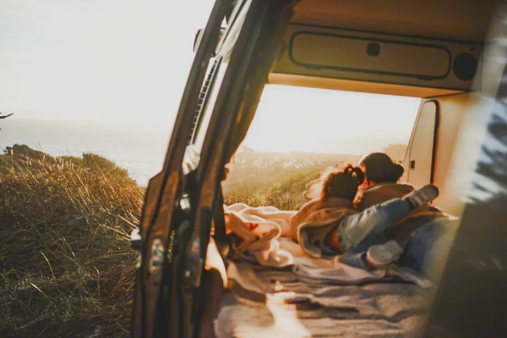 Cozy RV rental setup for two, overlooking the ocean at sunset. Relaxing inside a camper van with a stunning view.. Volkswagen Vanagon 1985