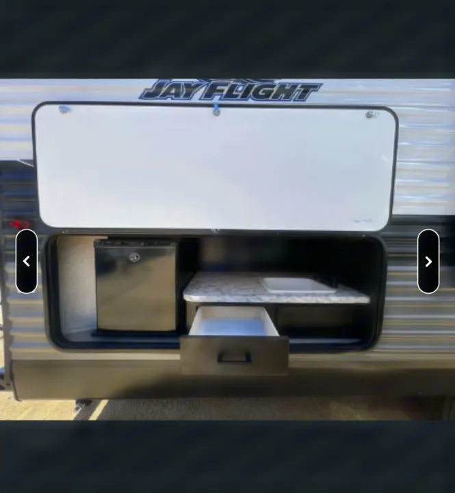 Outdoor kitchen of a Jay Flight RV rental, featuring a mini-fridge, sink, and pull-out drawer for convenient camping.. Jayco Jay Flight SLX Rocky Mountain Edition 2022
