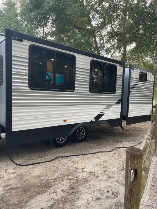 Spacious rv rental parked outdoors, ready for adventure. This travel trailer features a slide-out and modern design, ideal for camping.. Della Terra 312H Della Terra 2023
