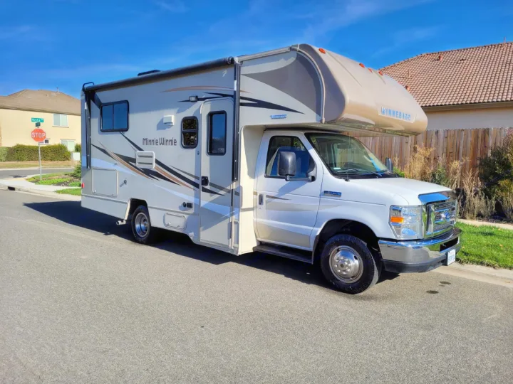 A modern white and beige Winnebago Minnie Winnie RV rental is parked on a sunny residential street.. Winnebago Minnie Winnie 2018