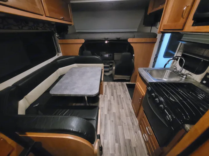 Spacious RV rental interior featuring dining, kitchen, and cab-over bed. Perfect for your next road trip adventure.. Winnebago Minnie Winnie 2018