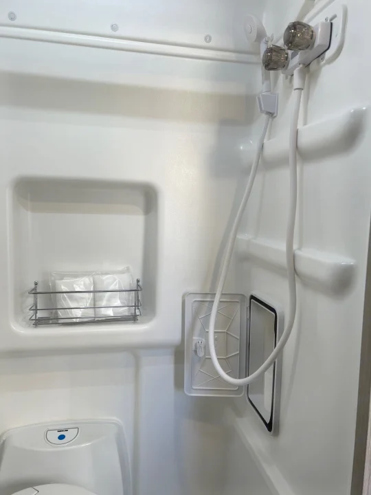 This compact RV rental bathroom showcases a shower, toilet, and convenient storage caddy for essential supplies.. Winnebago Solis 2023