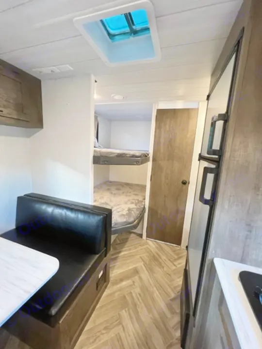 RV rental interior: view of the kitchen counter, two bunk beds with mattresses, and a black dinette seating area.. Forest River EVO Select 268 BH 2022
