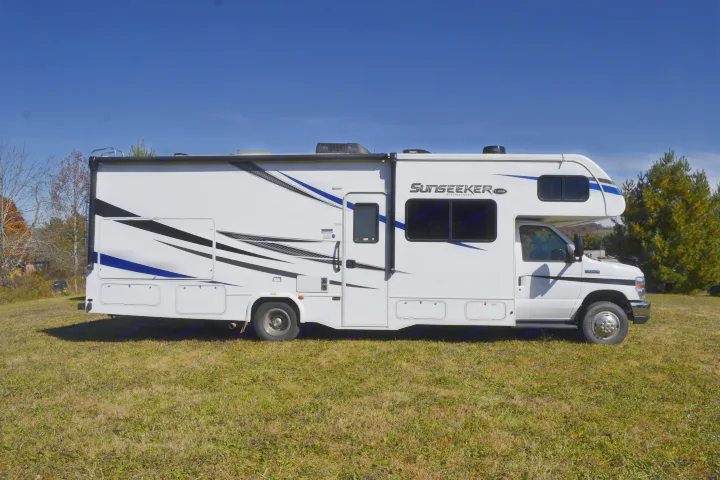 This Sunseeker Class C RV, a spacious rv rental option, showcases its white exterior with blue and black graphics on a sunny day.. Forest River Sunseeker Classic 2021