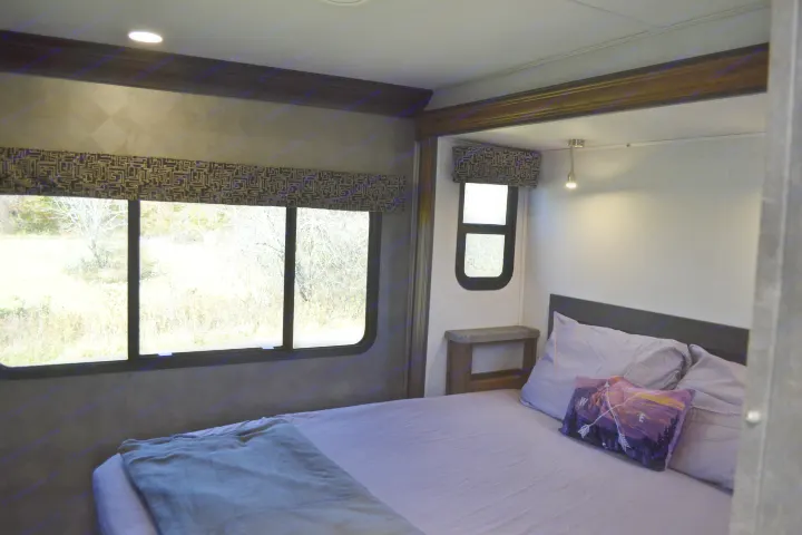 Spacious RV rental bedroom featuring a large window with a scenic view, comfortable bed, and compact design. Perfect for your next adventure.. Forest River Sunseeker Classic 2021