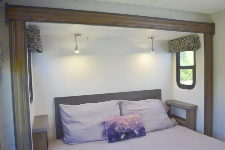 Cozy RV rental bedroom with comfortable bed, reading lights, and windows for a relaxing getaway.. Forest River Sunseeker Classic 2021